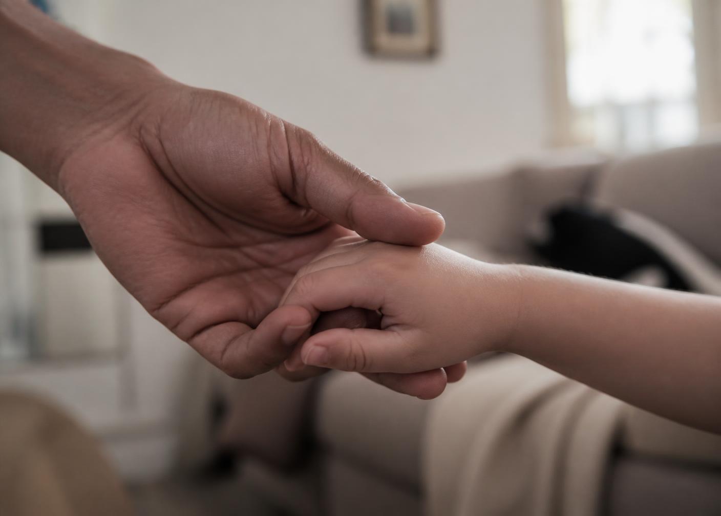 Erwachsenenhand hält die Hand eines kleinen Kindes